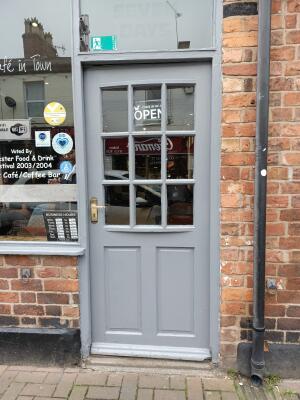 Grey wooden-panelled glass door ahead. Push from handle on left to open.
