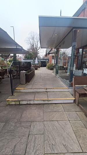 From left of outdoor front space facing straight. Open space ahead with steps. Hand rail on left.
