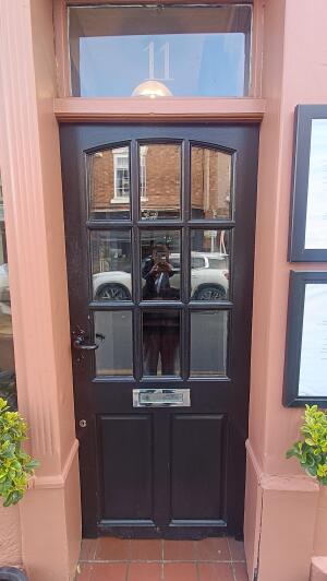 Black wooden-panelled glass door to venue. Push from handle on left to open.