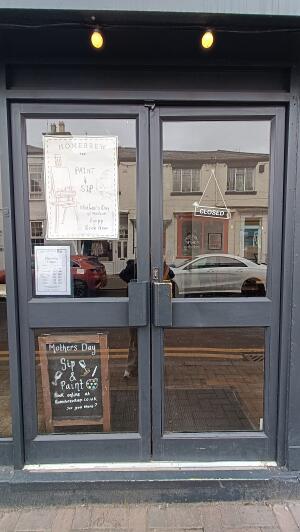 Dark grey metal-framed glass doors to venue. Push from handles at centre to open.