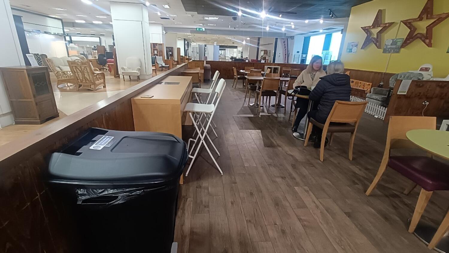 From entrance facing left. High table and stools along left. Chairs and tables along right.