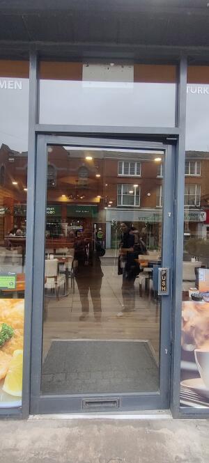 Dark metal-framed glass door ahead. Push from handle on right to open.
