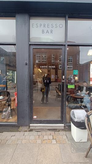 Black metal-framed glass door to venue. Push from handle on right to open.