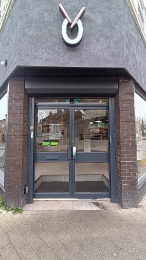 Dark metal-framed glass doors to venue. Push from handle in centre to open.