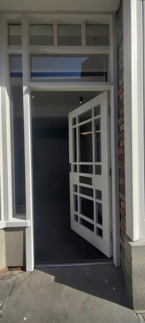 White wood-framed glass door. Push from handle on left to open.