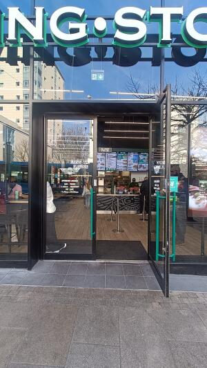 Black metal-framed glass doors to venue. Pull from handles at centre to open.