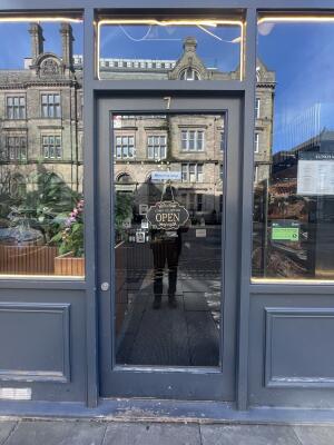 Dark blue metal-framed glass door. Push from left to open.