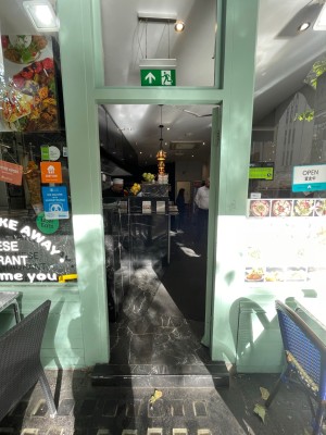Single glass door with green frame. Push metal handle on right to open.