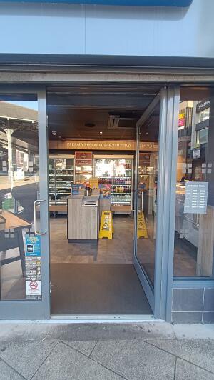 Grey metal-framed glass doors to venue. Push from handles at centre to open.