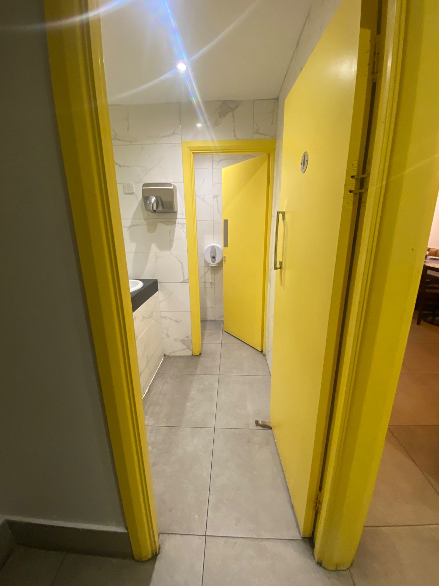 From landing of staircase, facing right to second door along right. Yellow wooden door, silver handle on left. Push to open.