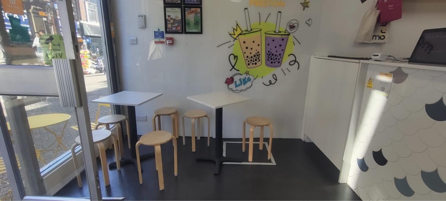 From entrance facing left. Tables with stools along back. Counter along right wall.