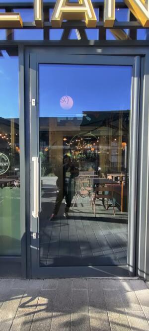 Dark metal-framed glass door. Pull from handle on left to open.