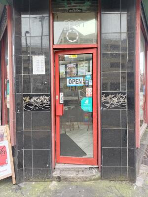 Red metal-framed glass door ahead. Push from handle on left to open.