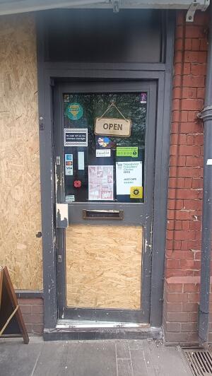 Dark grey metal-framed glass door to venue. Push from handle on left to open.