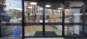 Black metal-framed glass doors. Automatic doors slide open from centre.