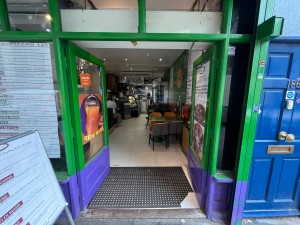 Green double doors with glass panels. Handle in centre, push to open.