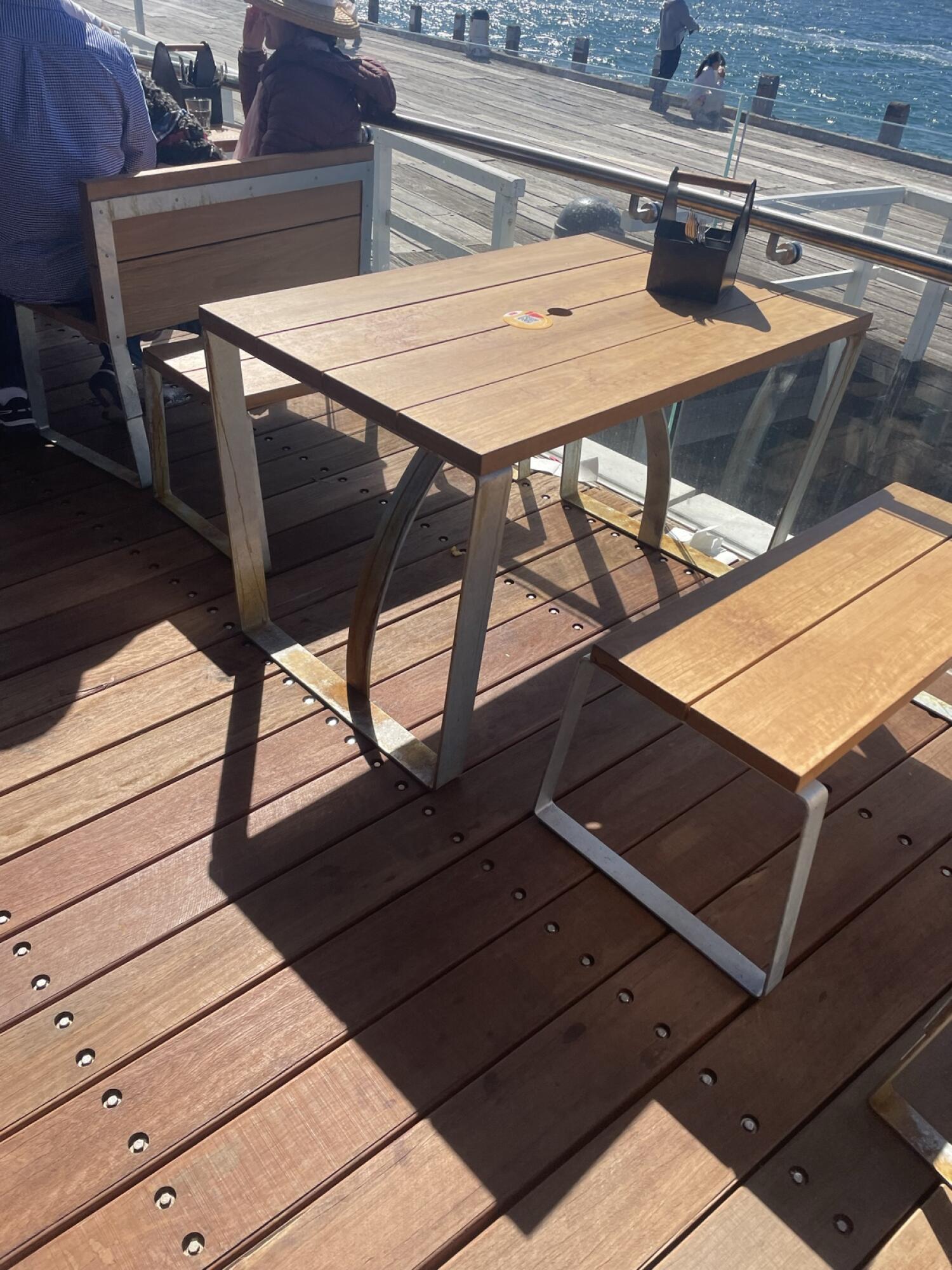 Bench along left. Wooden table with metal legs in centre. Bench along right facing table.