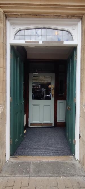 Green wooden doors ahead. Push metal handles at center to open.