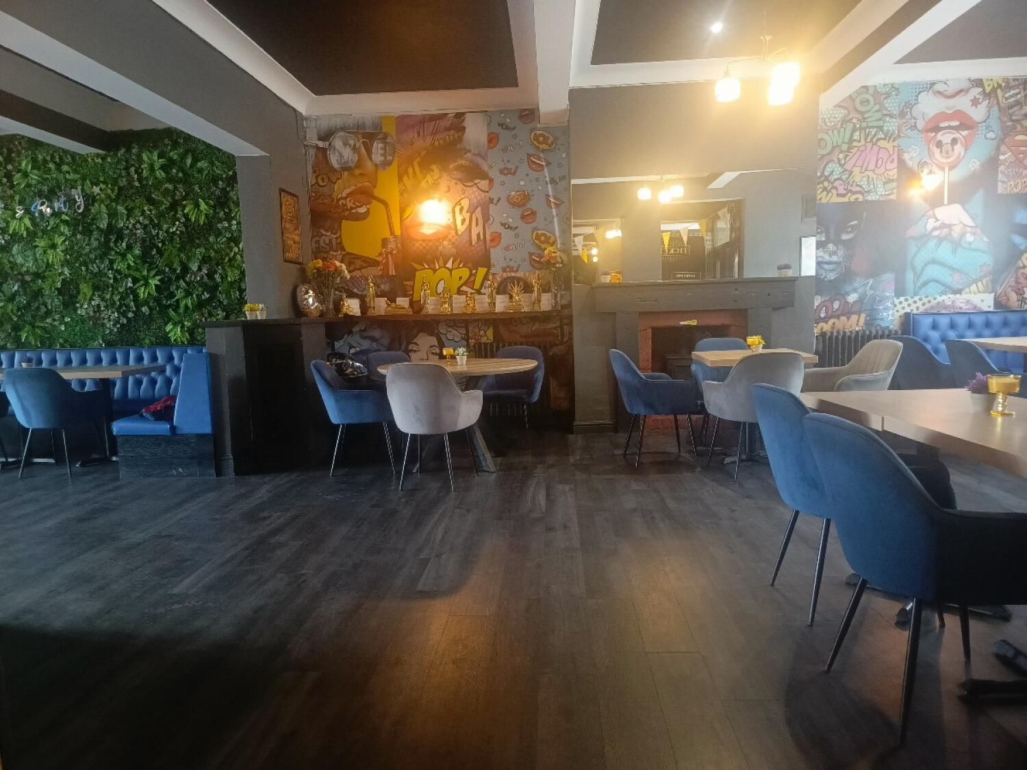 From entrance facing right. Booth seating along left wall. Tables and chairs in Back centre and right. Path at centre.