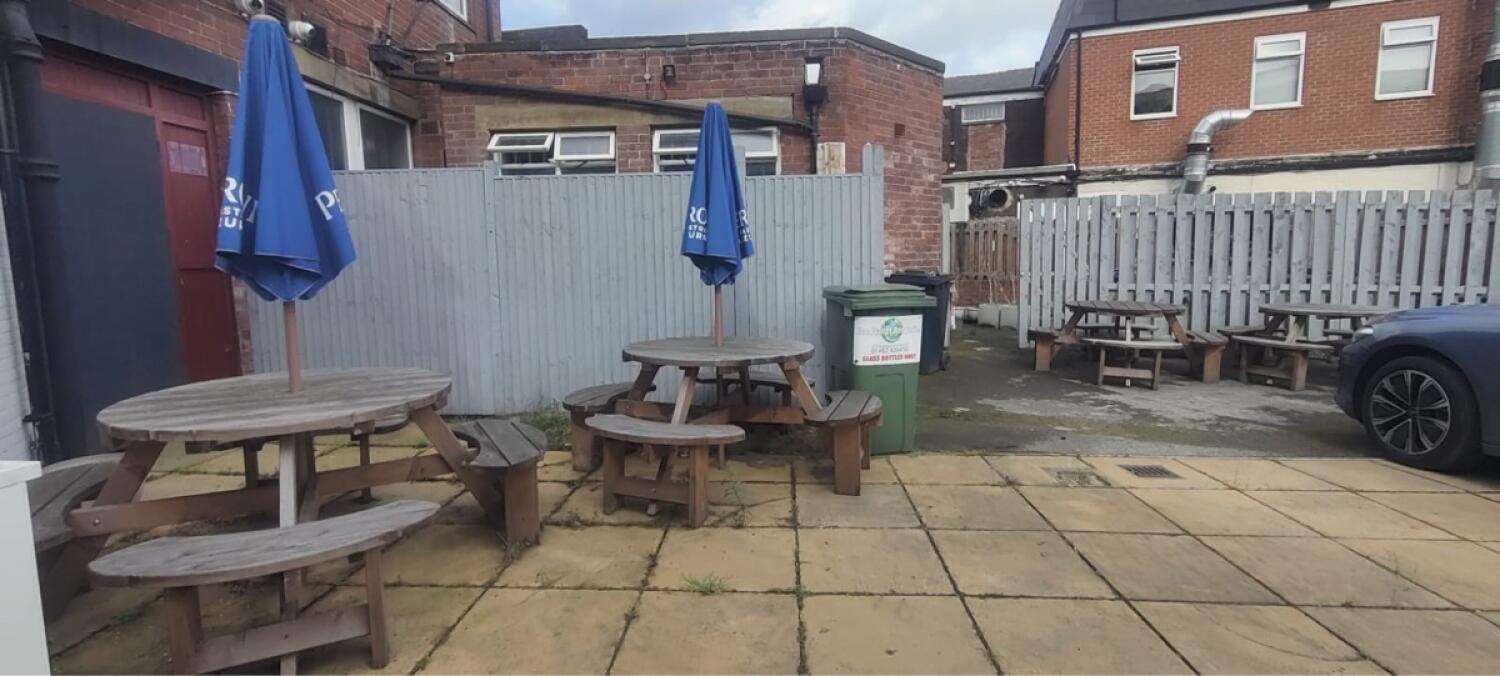 From end of steps facing straight. Picnic table with parasol on front left, centre and back right.