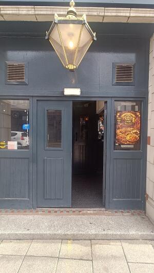 Dark grey wood-framed glass door to venue. Push handle in centre to open.