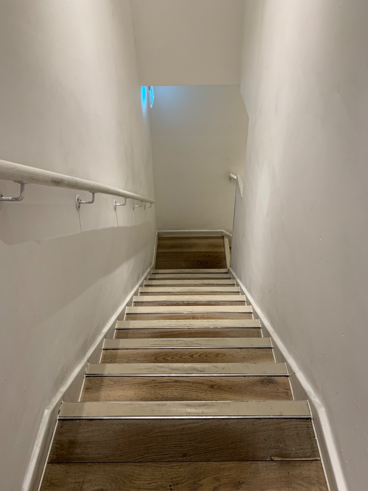 From doorway to toilet area, looking right. Staircase going down to landing ahead. Hand rail on left side.