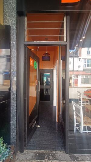 Black metal-framed glass door to venue. Push handle on right to open.