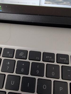 This image shows a close-up view of a laptop keyboard. It features black keys set against a silver metallic surface, including function keys like F7, F8, F9, prt sc (F10), and home (F11), positioned above the number and letter keys.