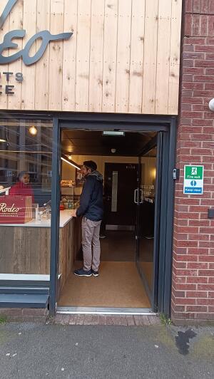 Dark grey metal-framed glass door to venue. Push handle on left to open.