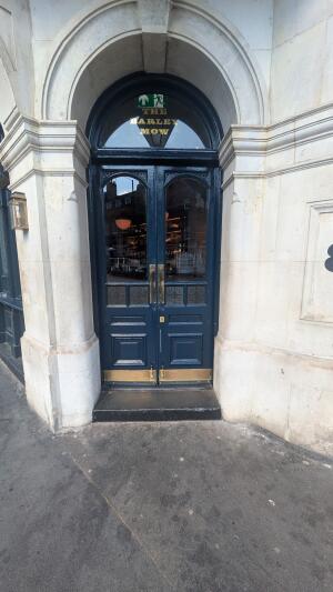 Dark blue wood-panelled glass doors. Push to open. One step up before door.