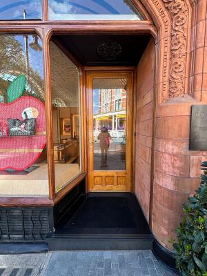 Open archway followed by a glass door with wooden frame. Use handle to open.