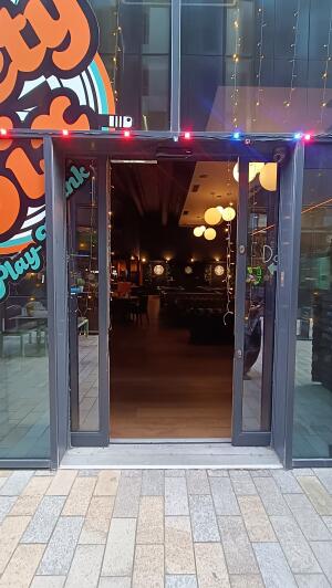 Grey metal-framed glass door to venue. Doors slide through centre.