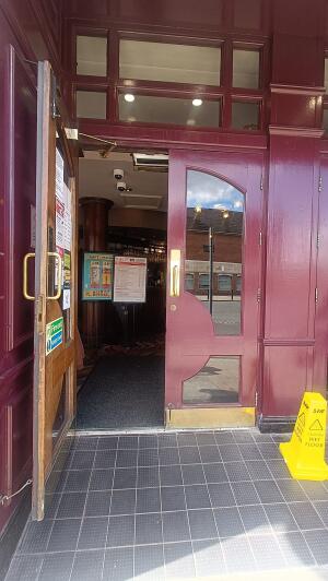Red framed glass panelled door to venue. Pull handle in centre to open.