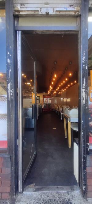 Black metal framed glass door ahead. Push metal handle on right to open.