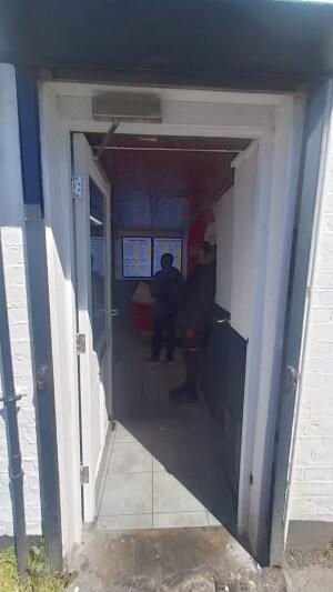 White wooden framed glass door ahead. Twist push metal handle at right to open.