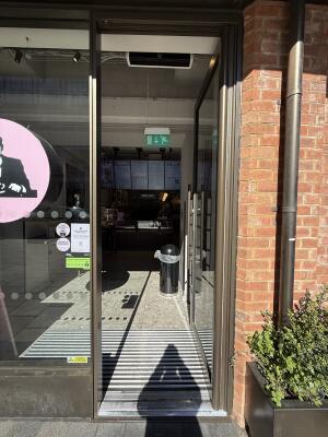 Glass door with metal frame ahead. Push from left to open.