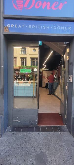 Grey metal framed glass doors ahead. Push metal vertical handle at centre to open.
