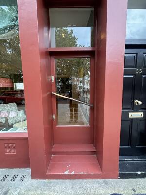 Red wood-framed glass door ahead. Push handle across door to open.