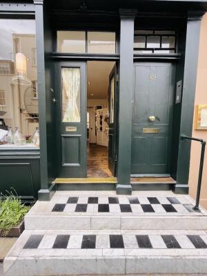 Three steps up before door. Dark green wooden door. Push from centre to open.