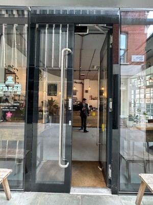 Double glass doors with black frame. Push silver vertical handles in middle to open.
