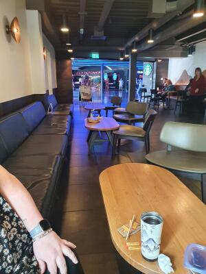 Bench seating along left wall. Path and tables in centre. Chairs and tables on right.