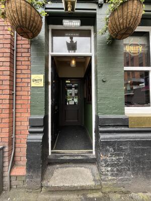 Black wooden door open. Interior corridor visible through doorway.