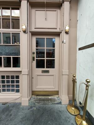 Pink wood-framed glass door. Use handle to open. Call for assistance button on top right.