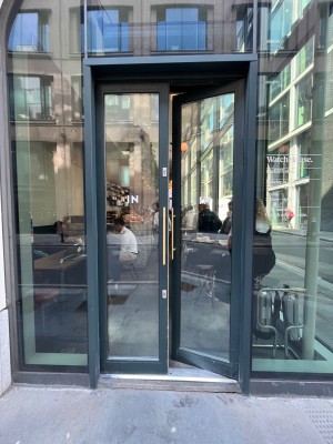 Glass doors with black frame. Push golden, metal handles in middle to open.