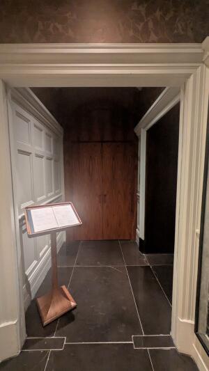 Archway ahead to wooden doors at back. Pull handles in centre to open. Menu board before door.