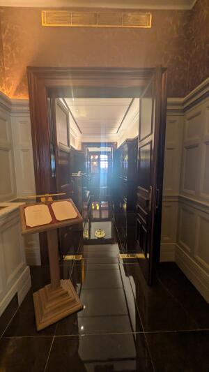 First set of wooden doors. Push in centre to open. Menu stand on left before doors.