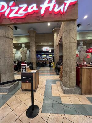 Opening ahead. Wide entrance into restaurant. Welcome desk on left.