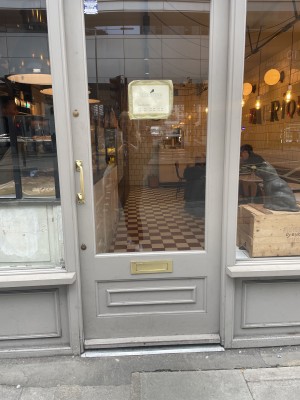 Single glass door with grey frame. Push golden handle on left to open.