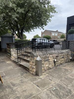 Paved path along left. Steps with handrails in centre. Stone wall along right.