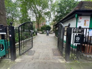 From street, facing entrance gate ahead. Black metal gate with black metal double doors. Push from center to open. Path straight to sign ahead.